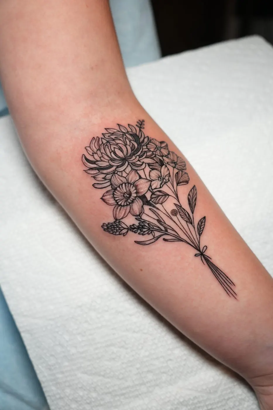 Black and grey bouquet of peonies tattooed on a forearm