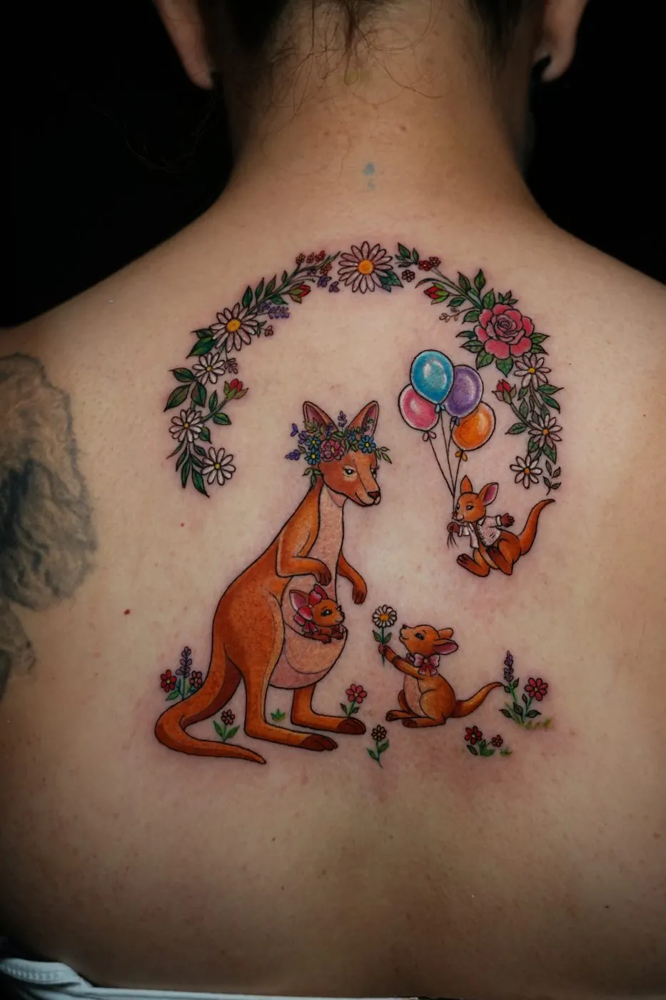 Colour tattoo of a kangaroo family with balloons across the upper back