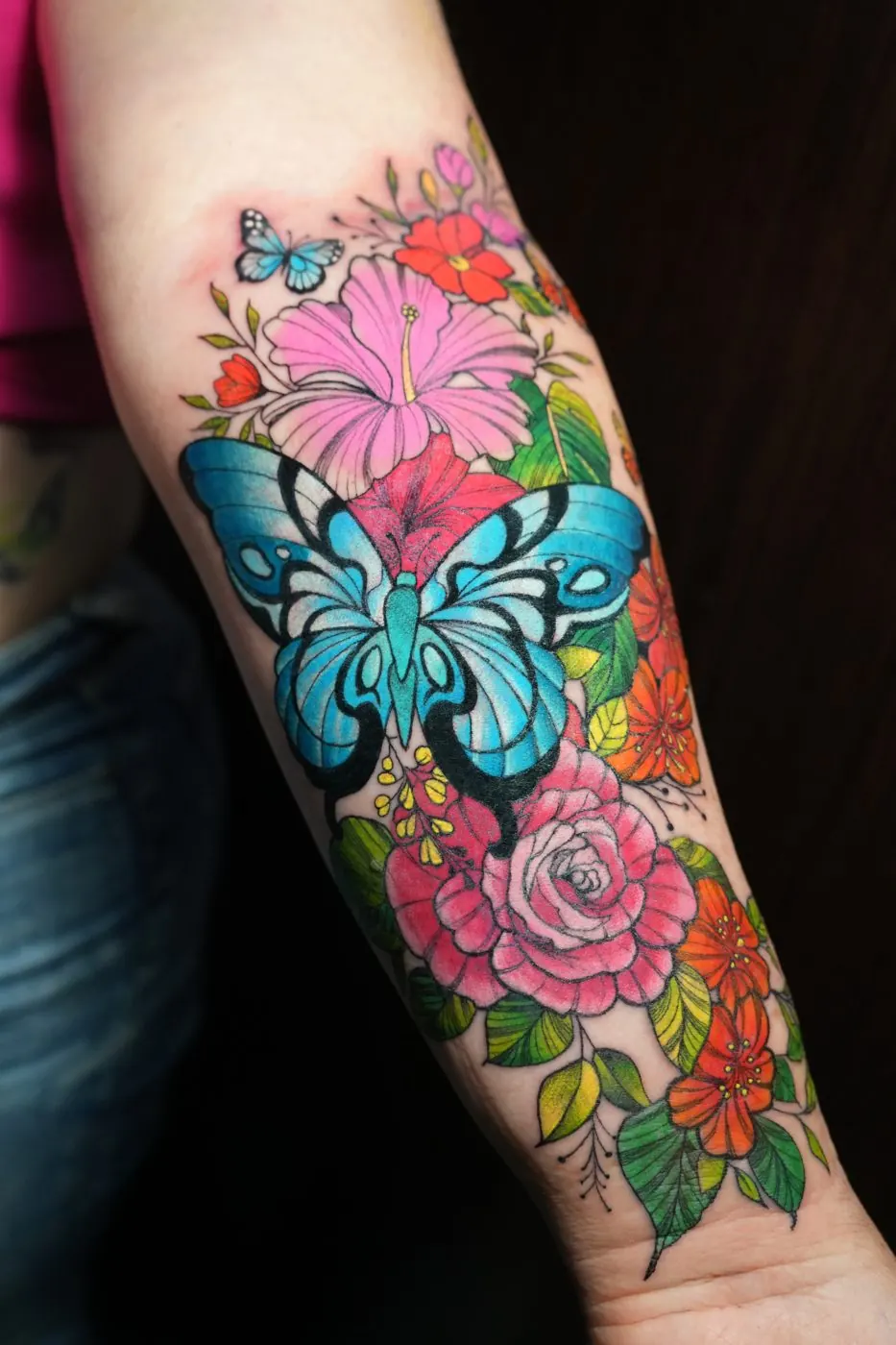 Vivid colour butterfly and flowers tattoo on a forearm
