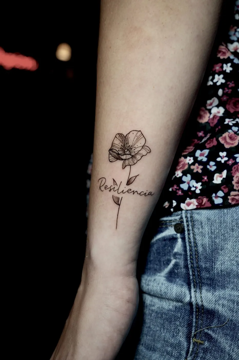 Small poppy flower tattoo with lettering on an arm