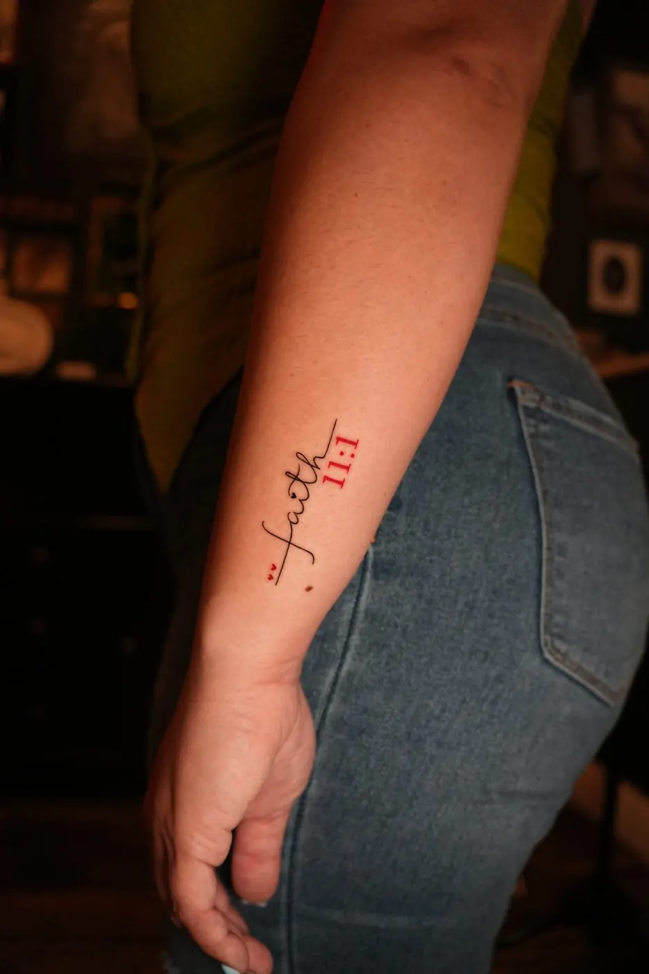 Small red lettering tattoo with 11:11 on a forearm