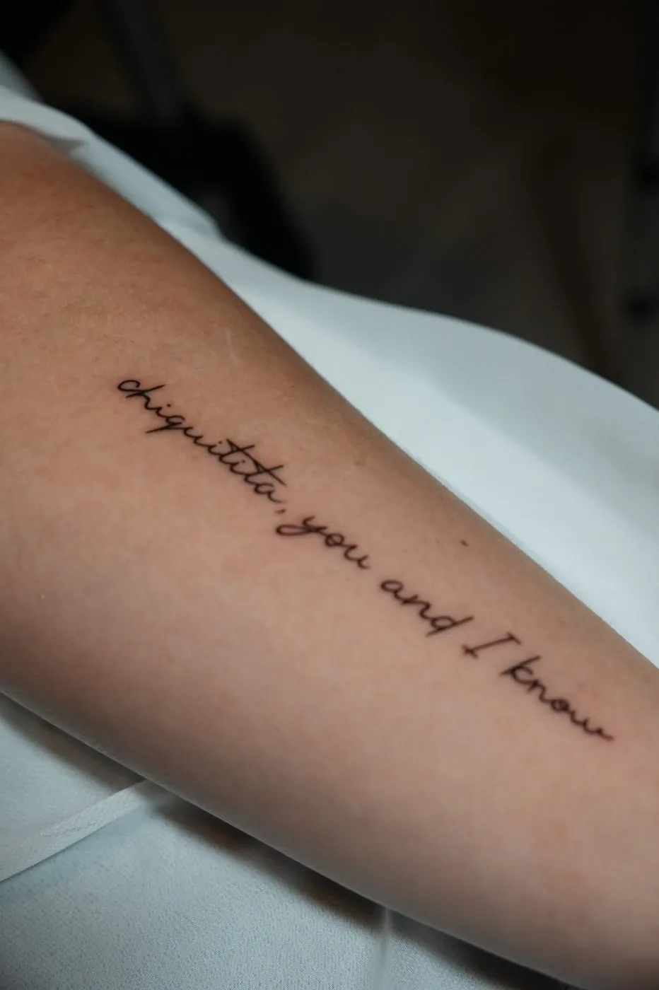Delicate handwritten script tattoo along the forearm