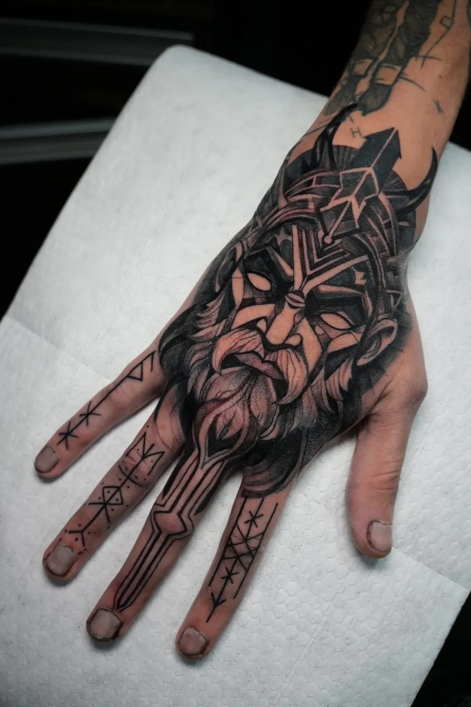 Geometric floral black work tattoo covering the hand and fingers
