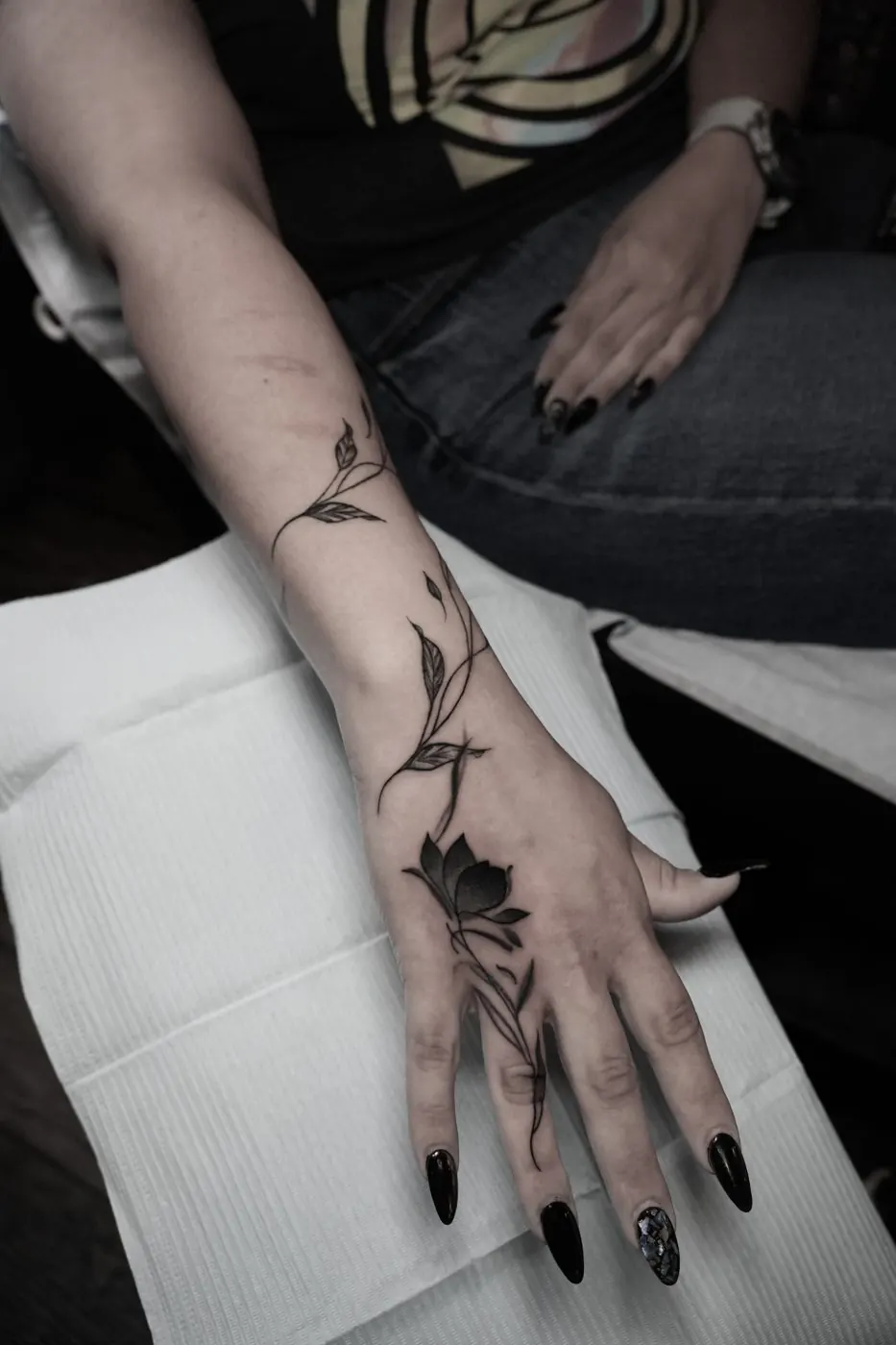 Fine line rose stem tattoo flowing from wrist to hand